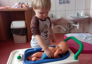 chłopiec myje lalkę w wanience